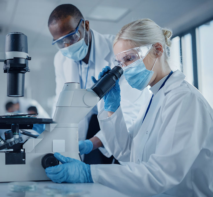 Lab technicians studying biological samples through a modern telescope.