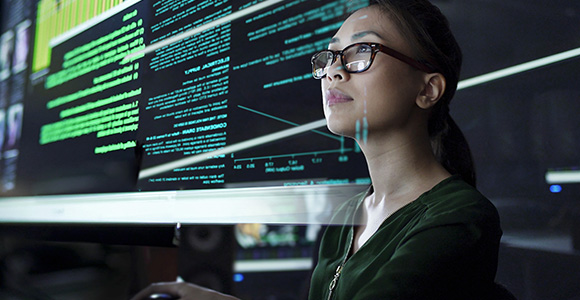 A professional stares at a large screen of data points and graphs.