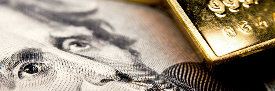 Closeup of a gold bar and an American 20-dollar bill.