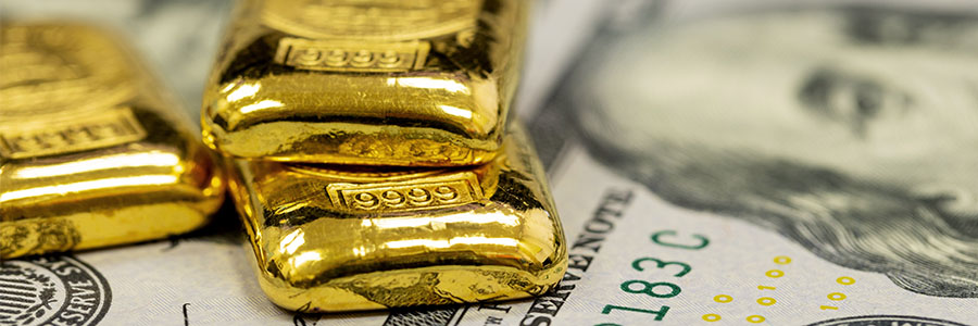 A stack of gold bullion on top of U.S. $100 bills