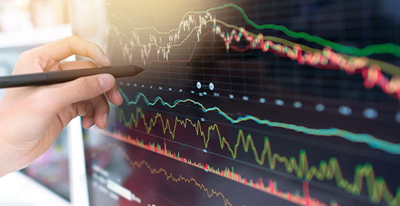 A professional uses a pen to point to different graphs on a computer screen.