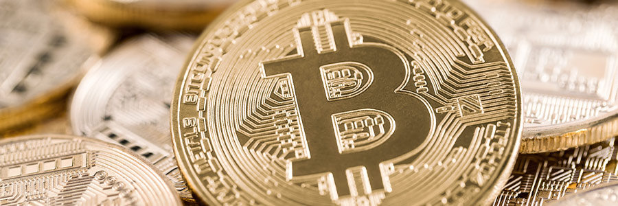 Close up of a gold-coloured coin printed with the Bitcoin currency symbol.