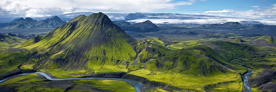 Aerial view of a mountainous landscape with green forests and a river.