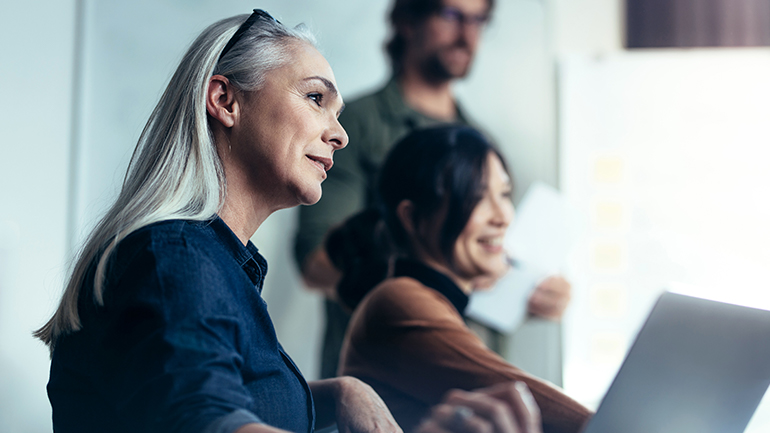 Image of 2 female colleagues smiling during an ongoing presentation